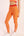 Eine Frau trägt eine orange Sportleggings mit einem roten Bund und einem  Bodyguard-Logo am Bein unten