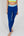 Eine Frau trägt eine dunkelblaue Sportleggings mit einem hellblauen Bund und einem gelben Akzentstreifen mit Bodyguard-Logoam Bein unten