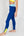 Eine Frau trägt eine dunkelblaue Sportleggings mit einem hellblauen Bund und einem gelben Akzentstreifen mit Bodyguard-Logoam Bein unten